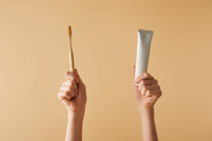 Close up of hands holding a toothbrush and toothpaste up high